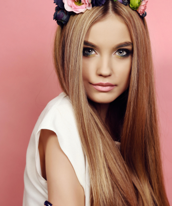Mujer joven con melena larga y lisa, diadema de flores y fondo rosa en retrato de primer plano.